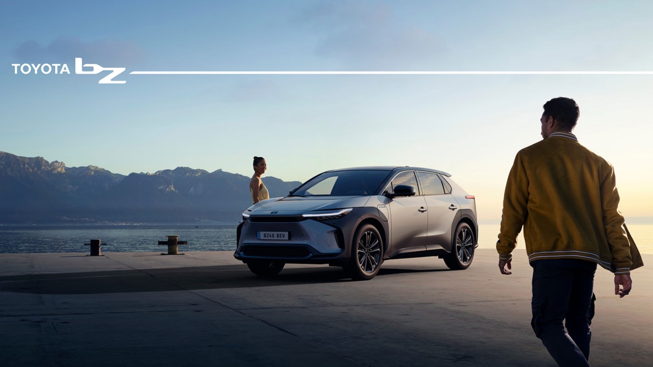 Two people standing next to a battery electric car